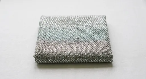 Close-up of a silver-threaded faraday fabric garment showing conductive fiber weave detail